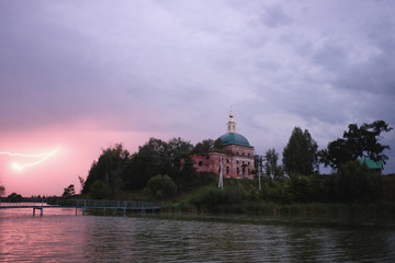 Fototapeta premium Ночной пейзаж с видом молнии над рекой и православного храма на берегу 