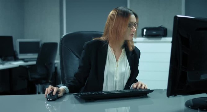 4K: Eine junge Managerin arbeitet an einem Computer in ihrem Buero. Ploetzlich freut sie sich ueberschwaenglich. Offensichtlich ein besonderes Ereignis.