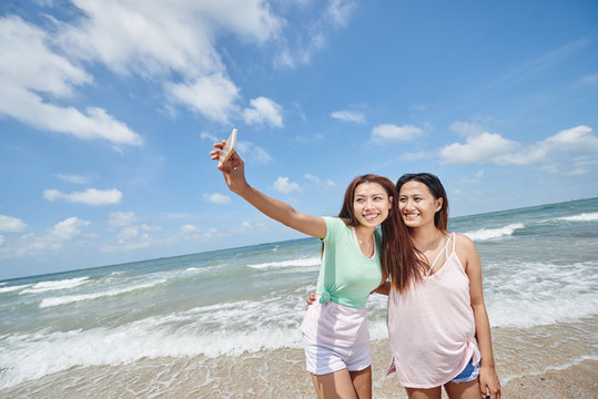 Pretty young Asian girls taking selfie on the beach