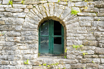 Fototapeta na wymiar Old broken window with spider web in old castle wall. Focus on window