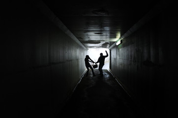 Man thief steals a bag from a woman in a dark tunnel