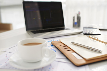 Coffee cup and notepad of business person on table