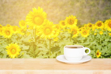 white cup coffee mug on wood desk and sunflowers background