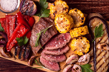 Grilled steak and vegetables on cutting board.