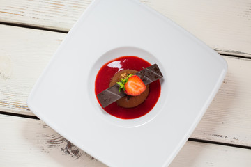 Small brown cake. Piece of strawberry and chocolate. Appetizing dessert with fresh berry. Sweet meal on kitchen table.