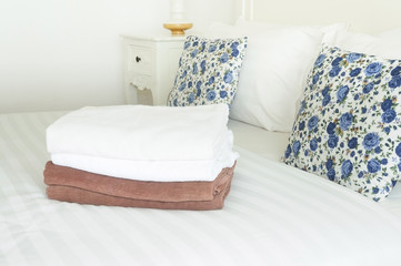 White and brown towels on clean bed with double pillows, bedroom