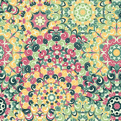 Fototapeta premium Seamless colorful ethnic pattern with mandalas in oriental style. Round doilies with green, pink, yellow curls and swirls weaving in arabesque traditional lace ornament. Vector illustration.