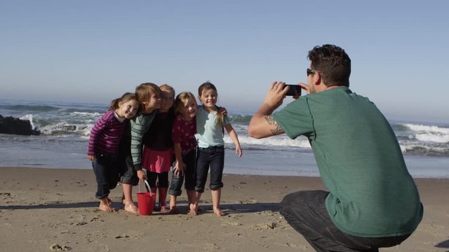 Family and friends taking group picture on the beach - 4K