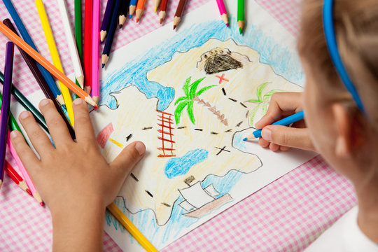 Child paints a picture of pencils pirate treasure map.