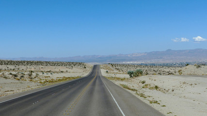 Highway durch die Wüste in Nevada/Lange, gerade Autobahn durch die Mojave-Wüste in Nevada, dreispurige Fahrbahn mit Markierung und Standstreifen, bergige Landschaft 