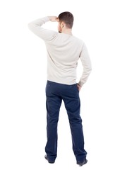 Fototapeta premium Back view of man . Standing young guy. bearded man in a white warm sweater covers her eyes.