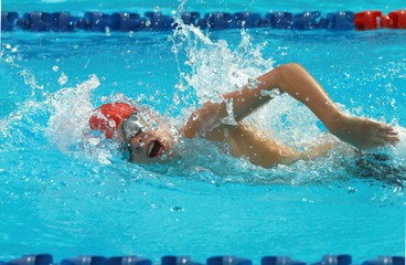 Fototapeta na wymiar Boy swimmer wearing red cap swim freestyle swimming stroke in a swimming pool