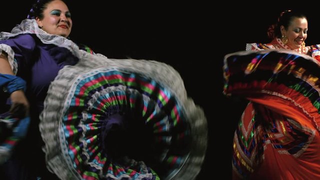 Slow motion shot of Mexican women in traditional dress dancing in the dark