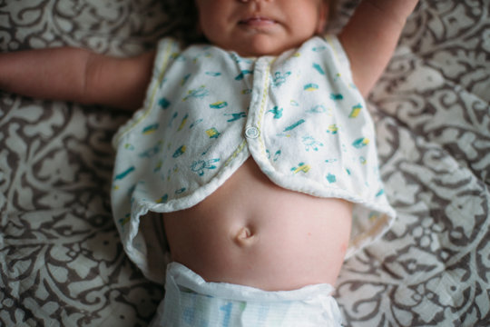 Baby lay on blanket with belly button showing, neck down 