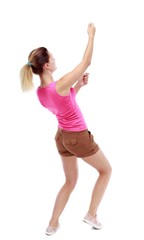 back view of standing girl pulling a rope from the top or cling to something. Isolated over white background. Sport blond in brown shorts hanging on a rope.