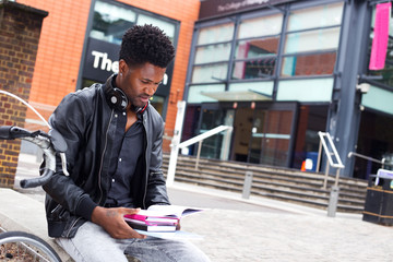 student sitting outside his college reading text books