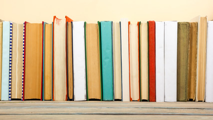 Books on grunge wooden table desk shelf in library. Back to school background with copy space for your ad text. Old hardback   no labels, blank spine