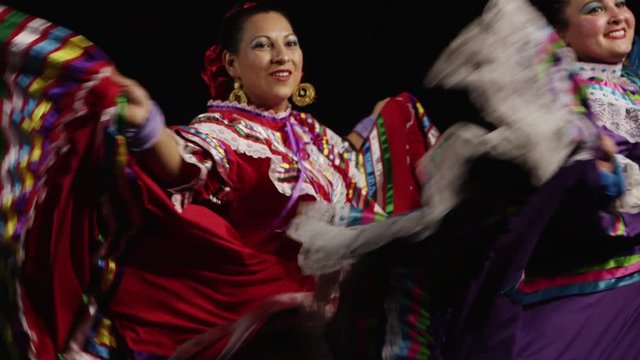 Slow motion shot of Mexican women in traditional dress dancing in the dark - 4K