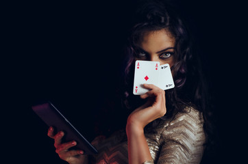 Mystic beautiful girl, covering face with cards and holding tablet in hand, online poker concept