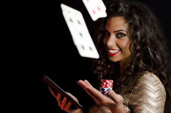 Cards flying in air, while girl holding poker chips and tablet