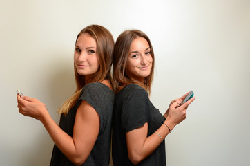 Zwei junge hübsche Mädchen Rücken an Rücken mit Handys