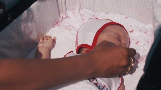 Mother give baby's dummy to crying baby in baby carriage. Summer day. Mothercare.