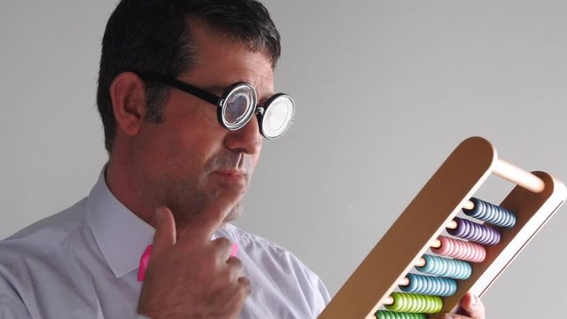 Geeky man accountant calculating with wooden numerator abacus. Finance, banking and economy concept. copy space