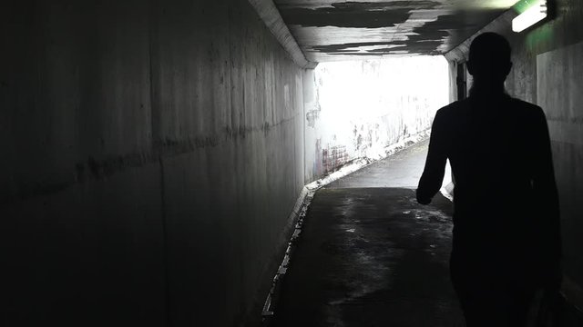 Silhouette of a man thief steals a bag from a woman in a dark tunnel. Violence against women concept. Real people, copy space