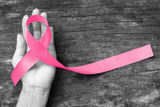 Breast Cancer pink ribbon awareness on woman hand, bow color concept raising awareness campaign on female patient with breast tumor illness (bow isolated with clipping path)