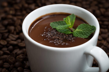 cup of hot mint chocolate on the background of coffee beans