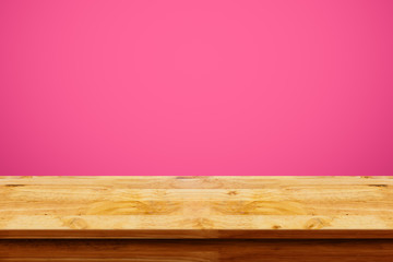 Empty top of wooden table on pink background.