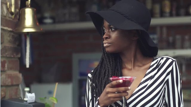 Gorgeous african american business lady drinking cocktail at bar with fancy interior