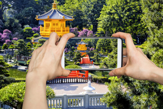 A tourist using smartphone camera to take a picture of the Pavilion of Absolute Perfection in Nan Lian Garden, Chi Lin Nunnery in Hong Kong