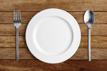  Empty white plate with silver fork and spoon on wood