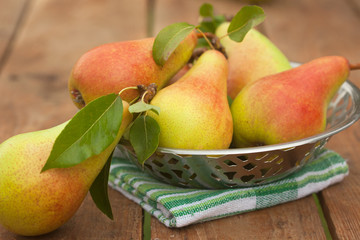 Ripe pears in fruit bowl on brown wooden table. Autumn concept.