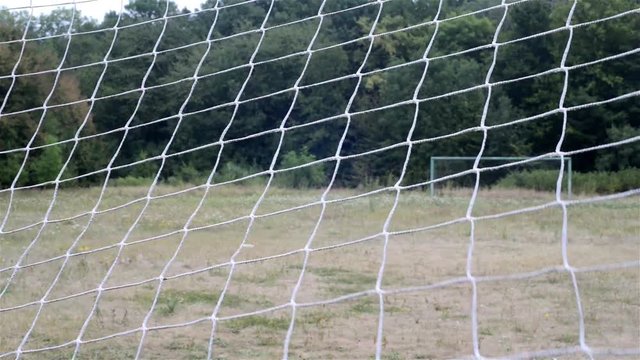 football net. football grid. view through the football net on the opposite gate. rural football field