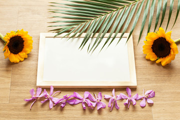White board covered with sunflowers, orchids and green leaves