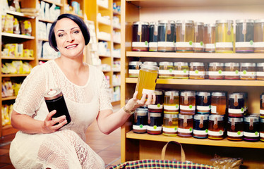 Woman choosing honey from assortment in drugstore