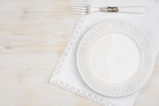 White ceramic plate with fork over placemat on wooden table