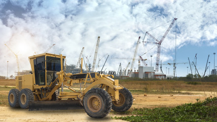Grader and building construction site against blue sky