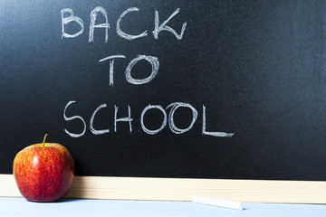 Red apple in fron of blackboard with the text 