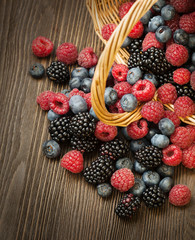 different berries in a basket on a wooden table