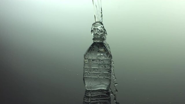 Slow motion shot of water pouring into bottle