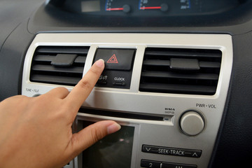 Hand touching emergency button in car