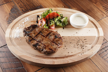 striploin beef steak with sauce on wooden surface. wooden background.