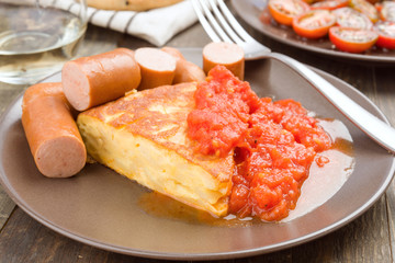 omelette with frankfurter and tomato in clay dish
