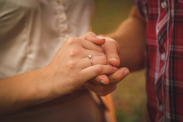 Delicate engagement ring put on the tender finger of young woman