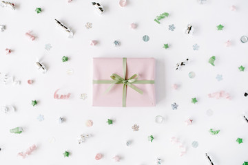 pink gift box with ribbon and bow on white decorated with tinsel background. flat lat, top view