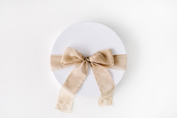 white gift cardboard box with brown bow on white background. flat lat, top view