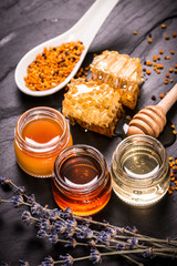 Honey in jar with honey dipper on black stone background
